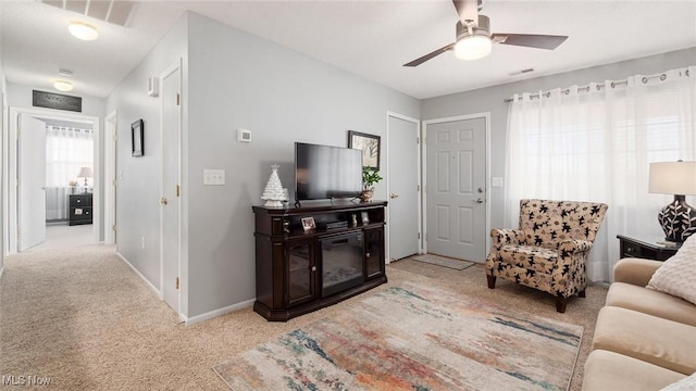 living room featuring light carpet, baseboards, visible vents, and ceiling fan