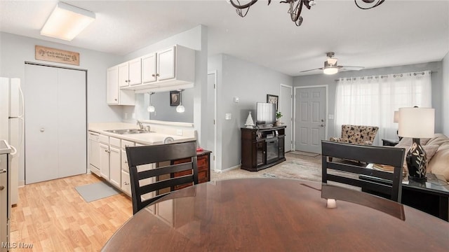 kitchen featuring a sink, white cabinetry, a ceiling fan, light countertops, and light wood-type flooring