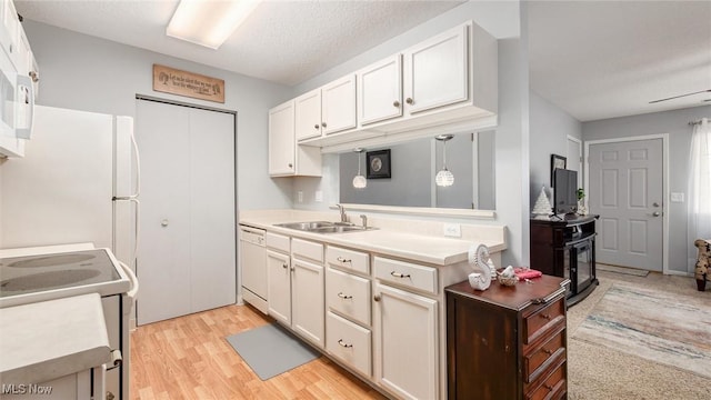 kitchen featuring decorative light fixtures, light countertops, white cabinetry, a sink, and white appliances