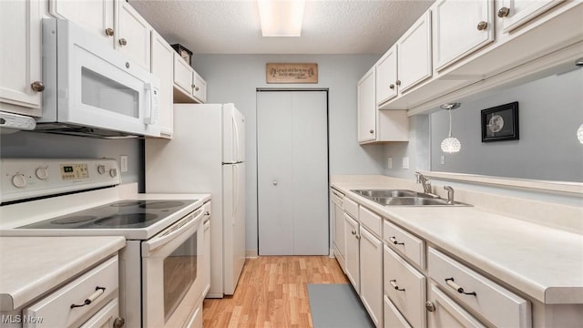 kitchen with light countertops, white appliances, decorative light fixtures, and white cabinets