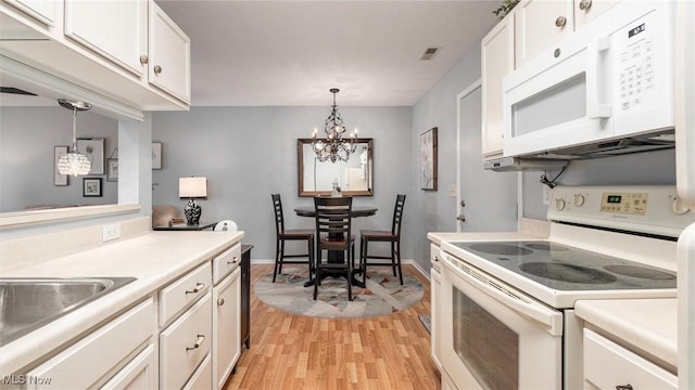 kitchen with white appliances, white cabinets, light wood-style flooring, hanging light fixtures, and light countertops