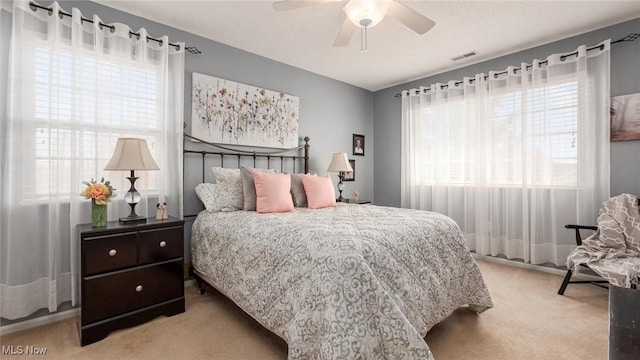 bedroom with light carpet, ceiling fan, and visible vents