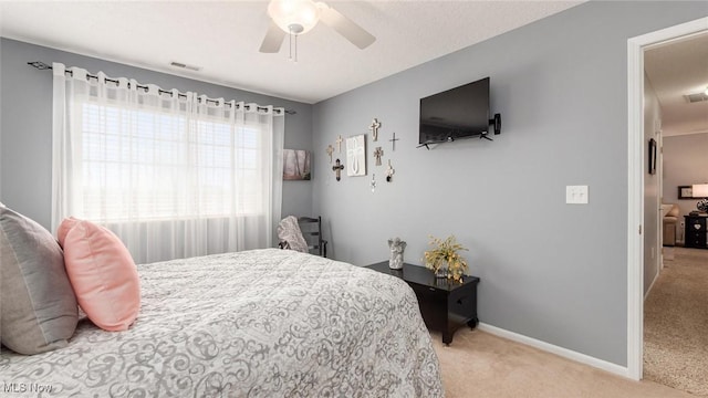 bedroom featuring light carpet, visible vents, baseboards, and ceiling fan