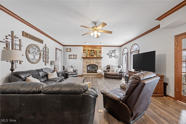 living room with a fireplace, wood finished floors, a ceiling fan, and crown molding