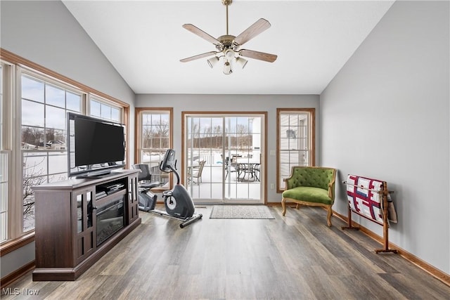 exercise area featuring dark wood finished floors, vaulted ceiling, baseboards, and ceiling fan