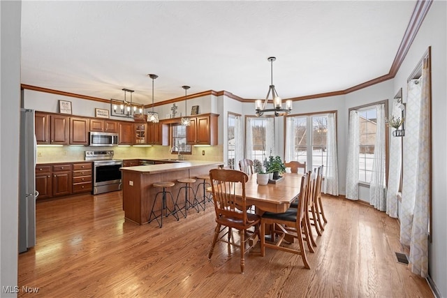 dining area with a chandelier, visible vents, ornamental molding, and wood finished floors