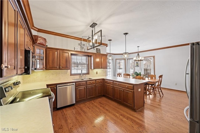 kitchen featuring light countertops, appliances with stainless steel finishes, a peninsula, and hanging light fixtures