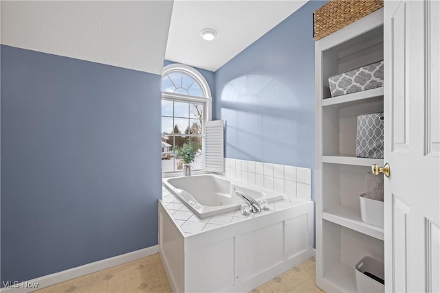 bathroom with a garden tub and baseboards