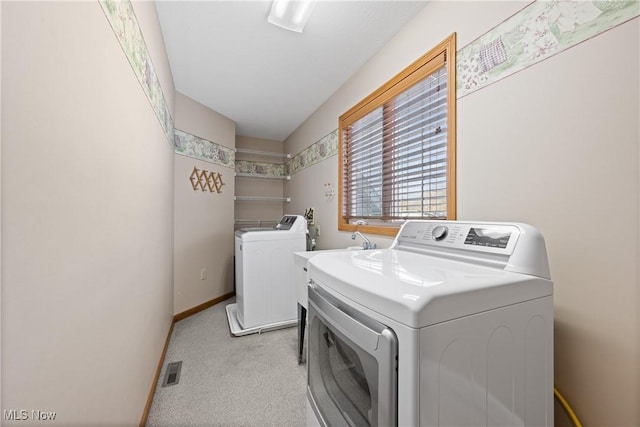 clothes washing area with laundry area, baseboards, visible vents, light colored carpet, and washer and dryer