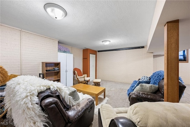 carpeted living area with a textured ceiling and brick wall