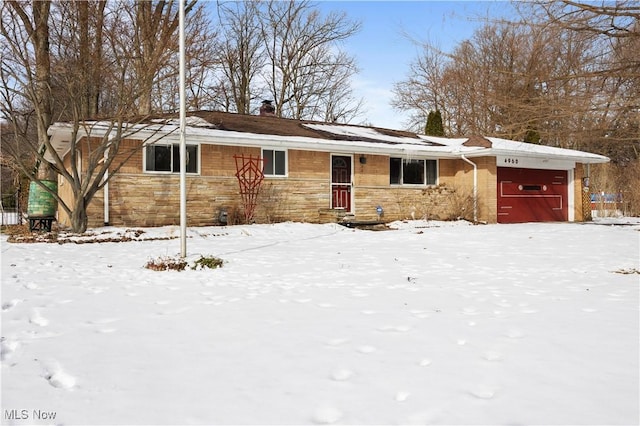 ranch-style house featuring stone siding, a chimney, and an attached garage