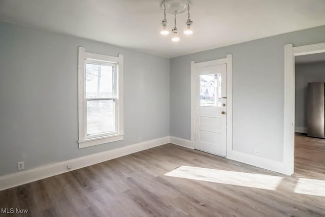 foyer featuring light wood-type flooring, a healthy amount of sunlight, and baseboards