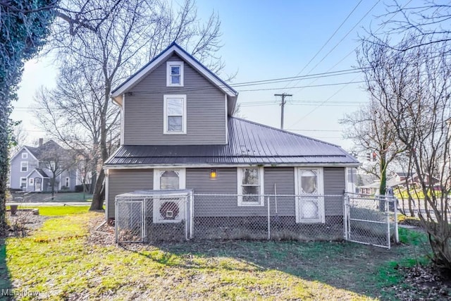 back of house featuring a fenced front yard, metal roof, and a lawn