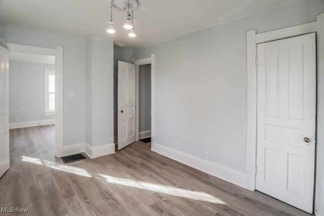 unfurnished bedroom with visible vents, light wood-style flooring, and baseboards