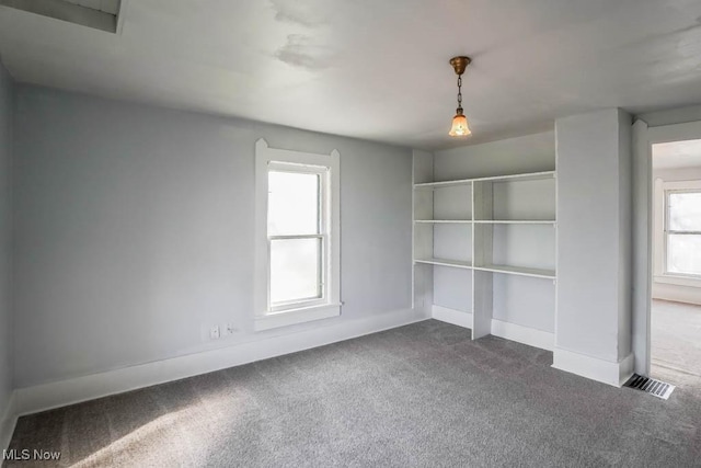 spare room with carpet floors, baseboards, and visible vents