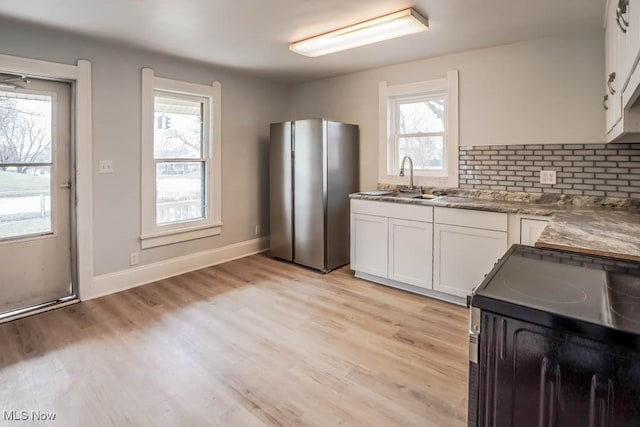 kitchen with tasteful backsplash, light wood-style flooring, electric range, freestanding refrigerator, and white cabinets