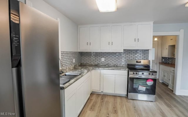 kitchen with light wood-style flooring, stainless steel appliances, a sink, white cabinets, and backsplash