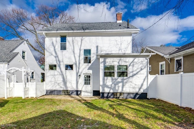 back of property featuring a yard, fence, and a chimney