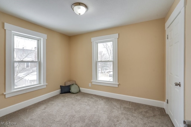 empty room featuring baseboards and light colored carpet