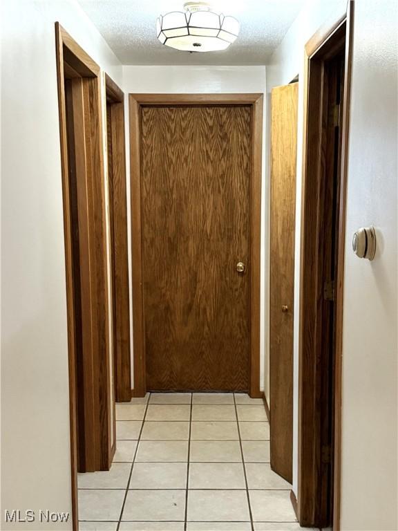 hallway featuring light tile patterned flooring and a textured ceiling