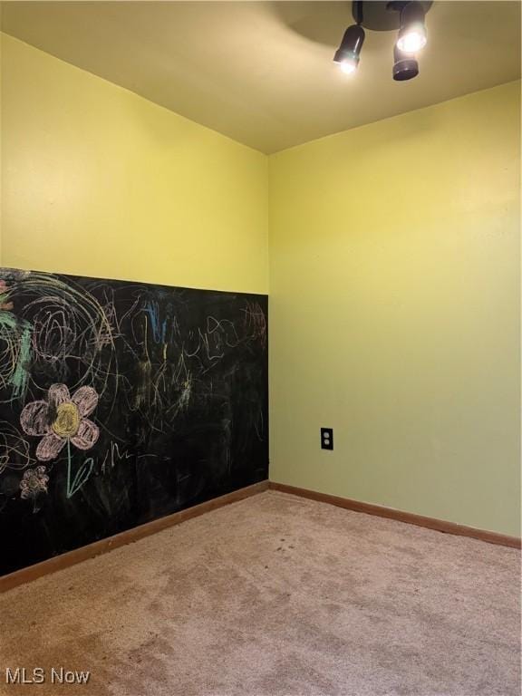 carpeted spare room featuring baseboards