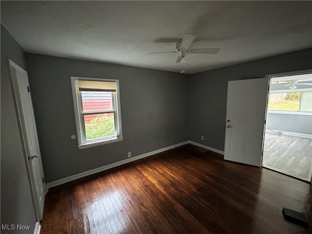 empty room featuring ceiling fan, baseboards, and dark wood-type flooring