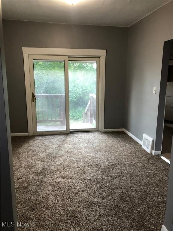 empty room featuring carpet, visible vents, and baseboards