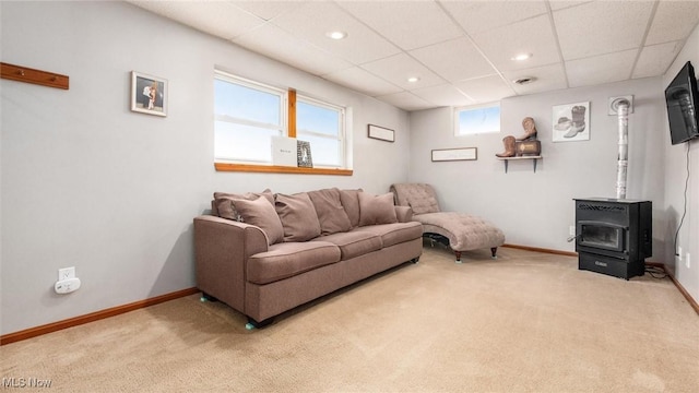 living area with baseboards, a wood stove, and light colored carpet