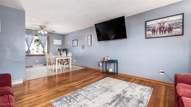 living area with a ceiling fan, baseboards, visible vents, and wood finished floors