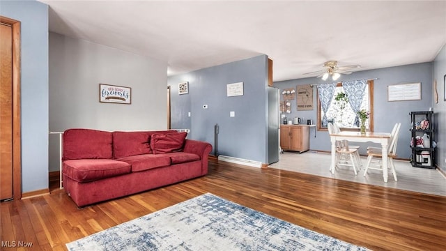 living area featuring ceiling fan, baseboards, and wood finished floors