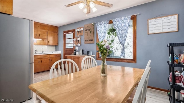 dining area featuring ceiling fan, light wood-style floors, and baseboards