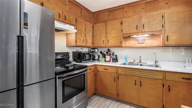 kitchen with light countertops, backsplash, appliances with stainless steel finishes, a sink, and under cabinet range hood