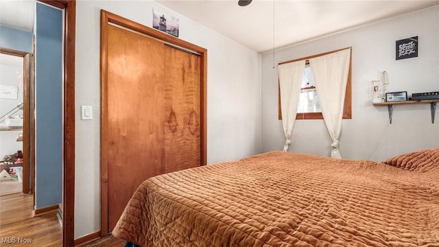 bedroom featuring a closet, wood finished floors, and baseboards