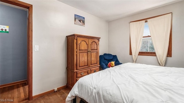 bedroom with baseboards and wood finished floors