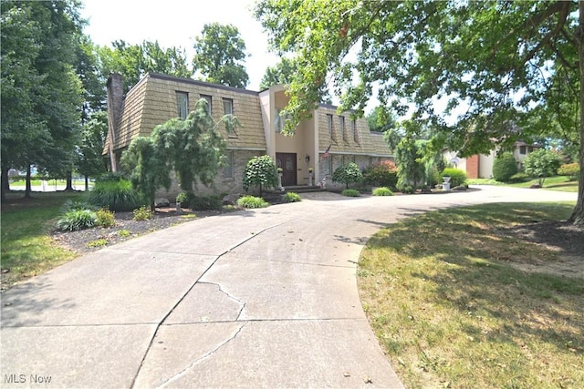 front of property with driveway, a front lawn, and mansard roof