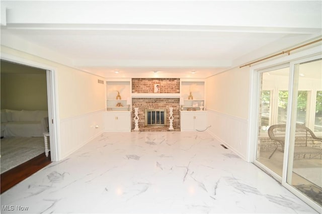 living area with marble finish floor, wainscoting, and a fireplace