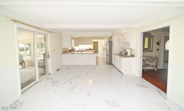 interior space featuring marble finish floor, wainscoting, and a decorative wall