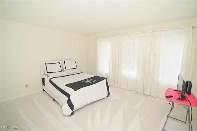 bedroom featuring light colored carpet and baseboards