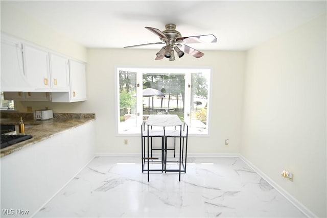 dining space with ceiling fan, marble finish floor, and baseboards