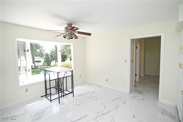 dining space featuring a ceiling fan, marble finish floor, and baseboards