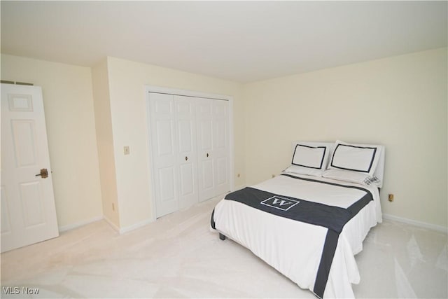 bedroom featuring light carpet, a closet, and baseboards