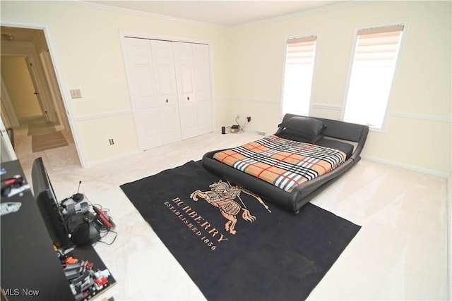 carpeted bedroom with ornamental molding, a closet, and baseboards