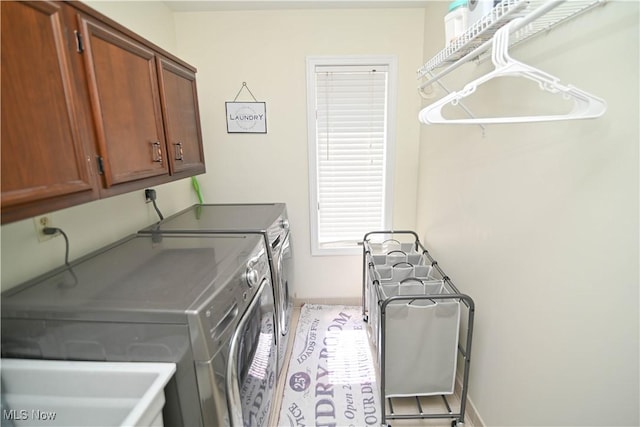 washroom featuring independent washer and dryer, cabinet space, and baseboards