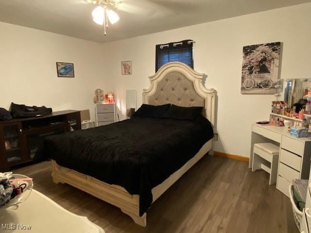 bedroom with a ceiling fan, baseboards, and dark wood-type flooring