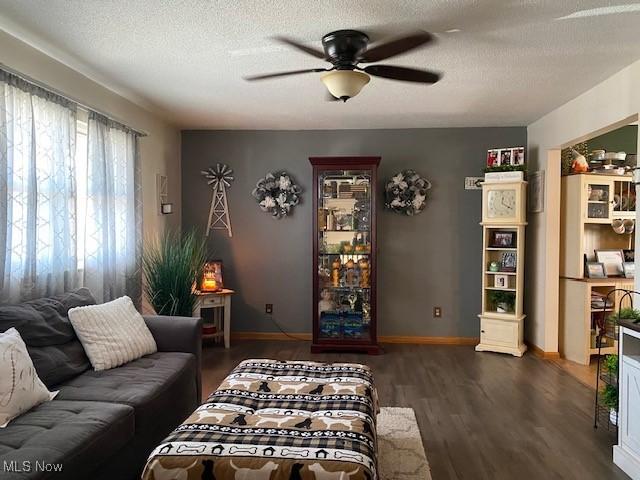 living room featuring dark wood finished floors, a textured ceiling, baseboards, and ceiling fan