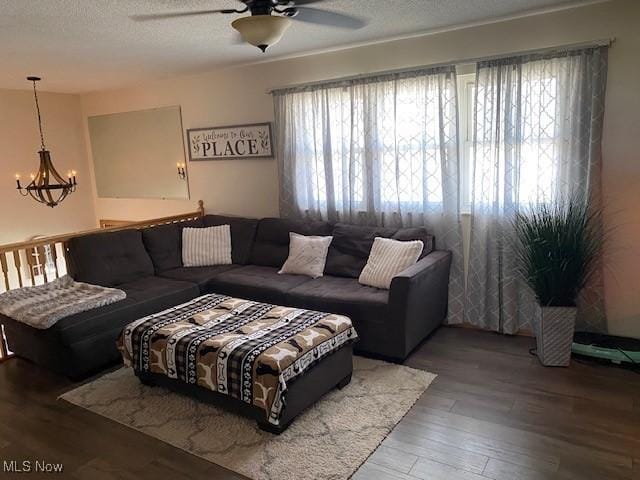 living area with ceiling fan with notable chandelier, a textured ceiling, and wood finished floors