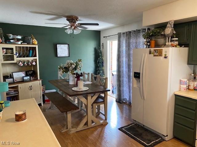 dining area with a ceiling fan, a textured ceiling, and wood finished floors