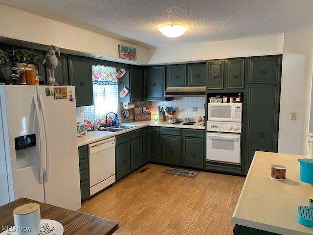 kitchen featuring under cabinet range hood, white appliances, a sink, light wood-style floors, and light countertops