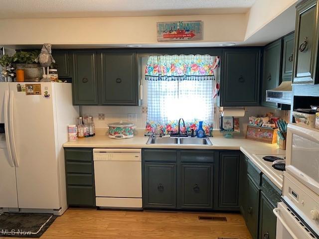 kitchen with white appliances, extractor fan, light countertops, light wood-style floors, and a sink