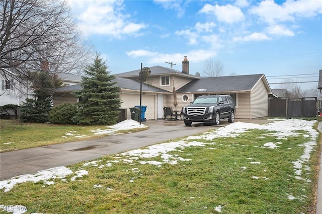 view of front facade featuring a front yard, driveway, a chimney, and an attached garage